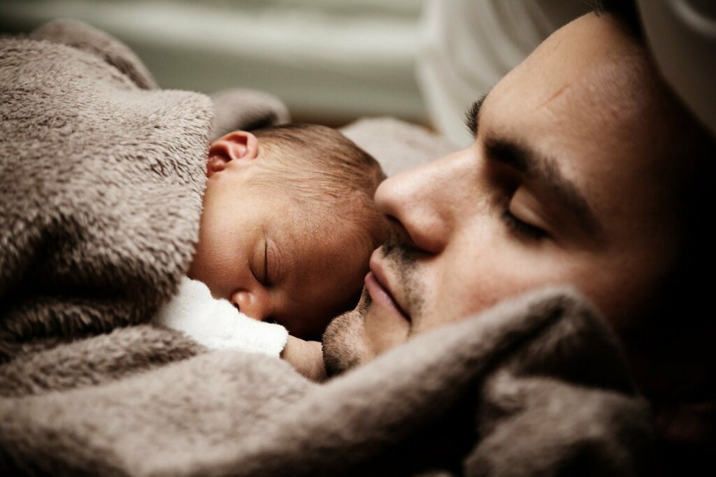 Baby schläft friedlich bei Vater Wann Baby ins Bett bringen