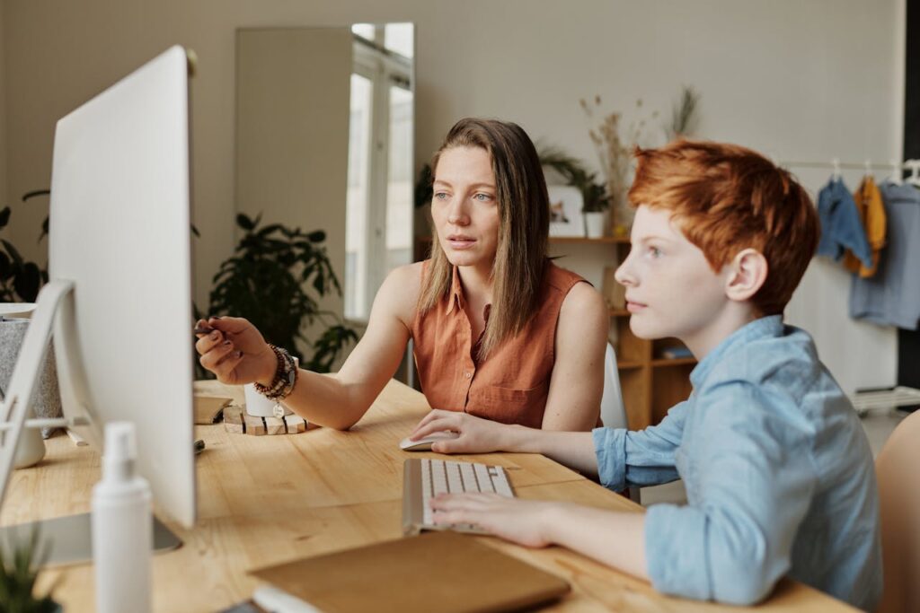 Mutter erklärt Kind am PC Medienkompetenz bei Kindern fördern – Tipps für Eltern und Erzieher